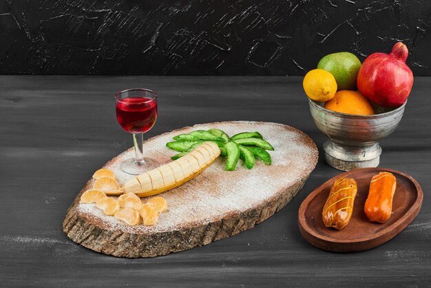 Eclairs con composición de frutas y una copa de vino.