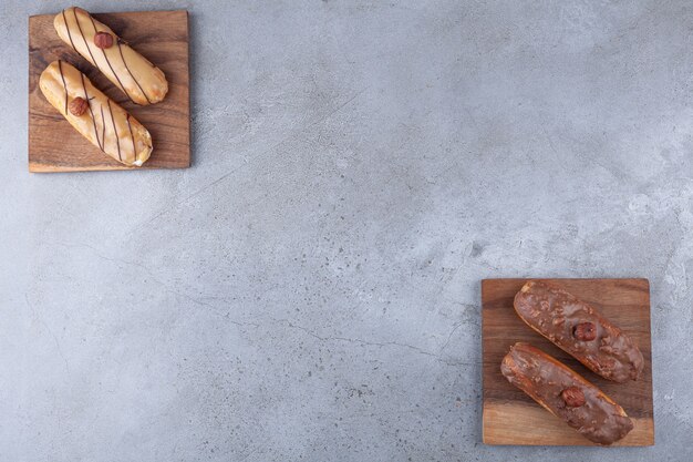 Eclairs franceses tradicionales con chocolate colocados sobre tabla de madera.