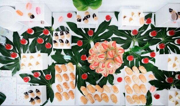 Eclairs de fresa servido en plato transparente de pie sobre una mesa con otros dulces