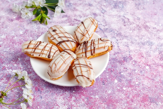 Eclairs o profiteroles con chocolate negro y chocolate blanco con natillas dentro, postre francés tradicional. Vista superior.