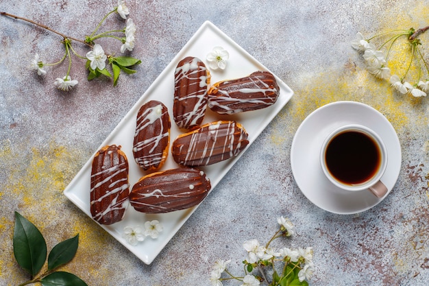 Eclairs o profiteroles con chocolate negro y chocolate blanco con natillas dentro, postre francés tradicional. vista superior.