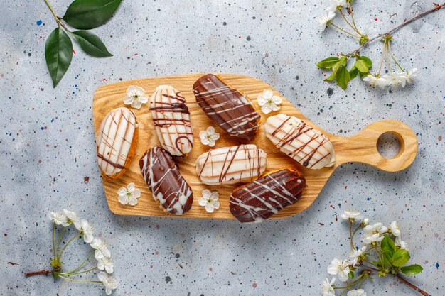 Eclairs o profiteroles con chocolate negro y chocolate blanco con natillas dentro, postre francés tradicional. Vista superior.