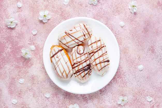 Eclairs o profiteroles con chocolate negro y chocolate blanco con natillas dentro, postre francés tradicional.