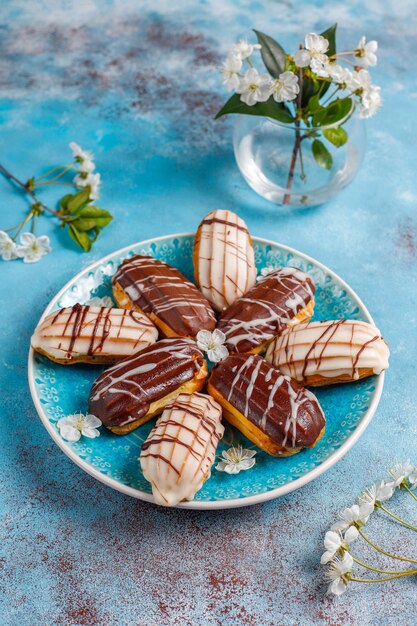 Eclairs o profiteroles con chocolate negro y chocolate blanco con natillas en el interior, postre tradicional francés.