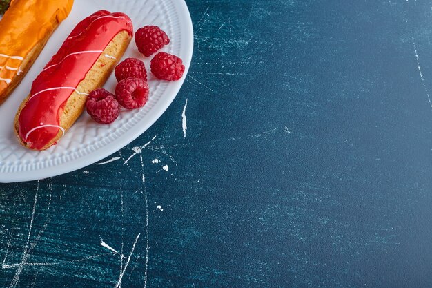 Eclairs con salsa de frambuesa por encima.