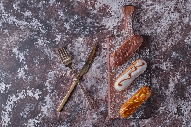 Eclairs en una tabla de madera, vista superior.