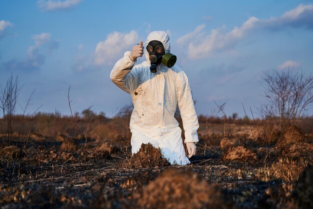 Ecologista que examina el suelo en el campo después del fuego