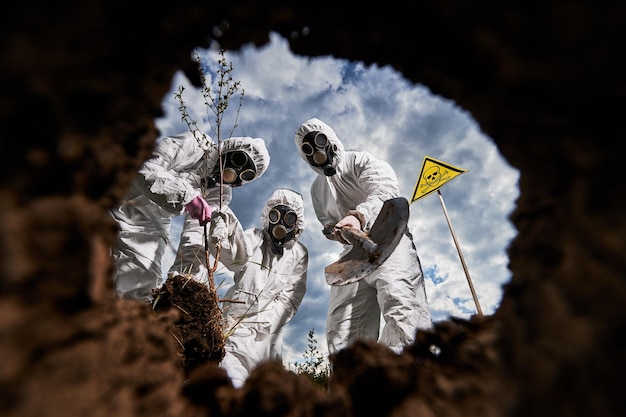 Foto gratuita ecologistas cavando pozos con pala y plantando árboles en áreas contaminadas