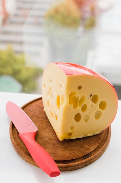 Edam trozo con cuchillo rojo sobre tabla de madera