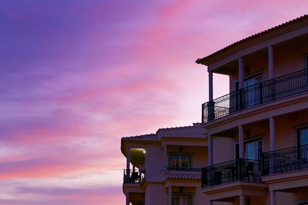 Edificio con balcones bajo la hermosa puesta de sol rosa sk