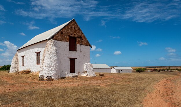 Edificio blanco en un campo de una granja en una zona rural bajo el cielo nublado