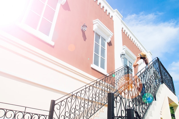 Edificio clásico con perspectiva atractiva y mujer turística en vestido blanco y sombrero