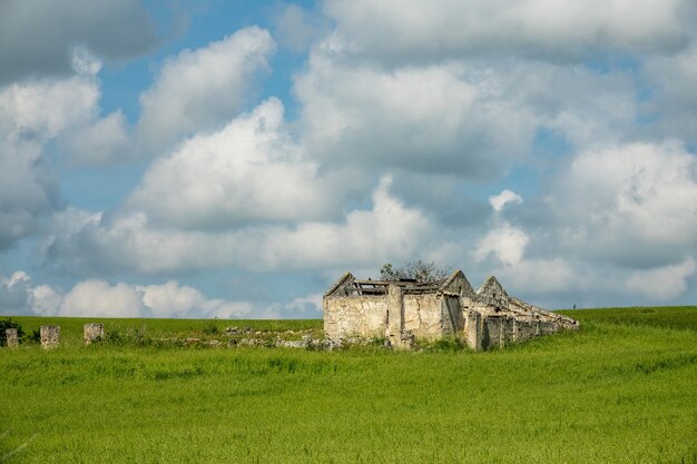 Edificio construido sobre un campo verde bajo un cielo lleno de nubes durante el día