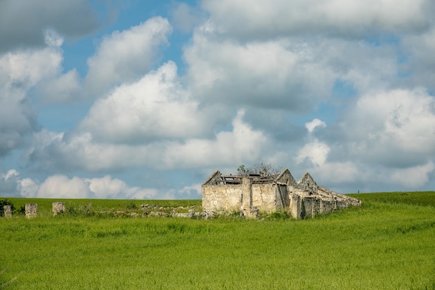 Edificio construido sobre un campo verde bajo un cielo lleno de nubes durante el día