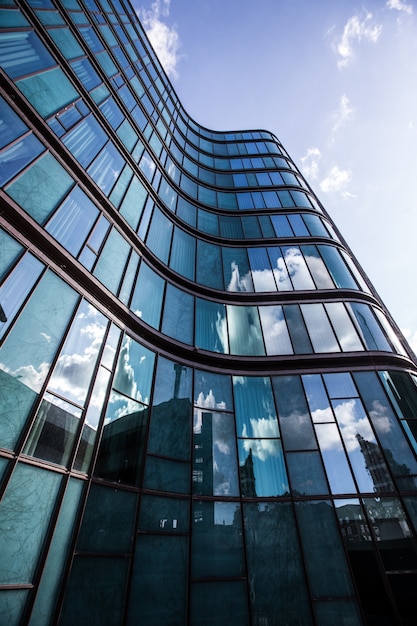 Un edificio de gran altura en una fachada de vidrio con el reflejo de los edificios circundantes.