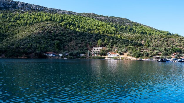 Edificios y barcos amarrados cerca del agua, mucha vegetación, colinas verdes, Grecia