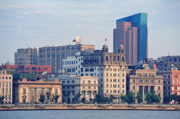 Edificios históricos y urbanos de Shanghai sobre el río Huangpu en la mañana con cielo azul.