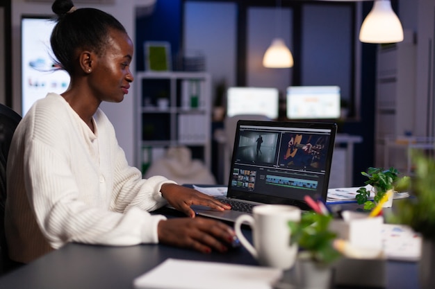 Editor de video afroamericano trabajando hasta altas horas de la noche en un proyecto de película digital