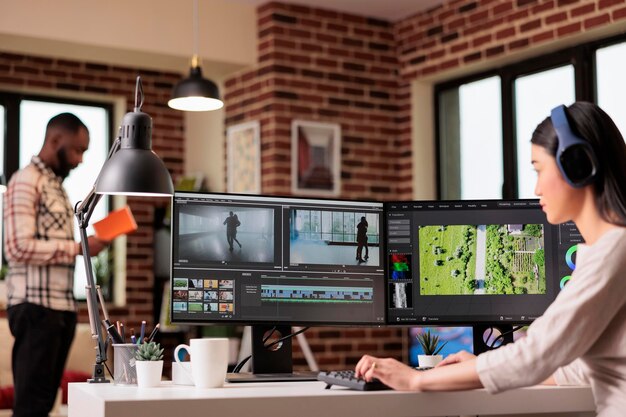 Editor de video asiático que trabaja con imágenes multimedia, edita montajes de películas con gradación de color y sonido, trabaja de forma independiente en casa. Uso de software de postproducción para hacer películas.