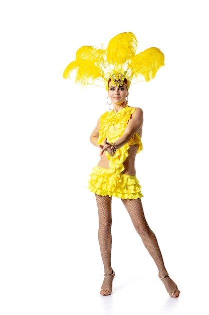 Ejecutando. Hermosa mujer joven en traje de mascarada de carnaval con plumas amarillas bailando sobre fondo blanco. Concepto de celebración navideña, tiempo festivo, baile, fiesta, felicidad. Copyspace