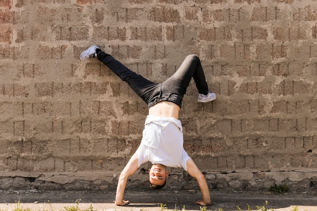 Ejecutante masculino haciendo danza de hip-hop contra la pared