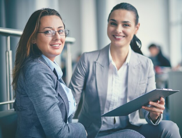 Ejecutivas bien vestidas sentadas en el sillón