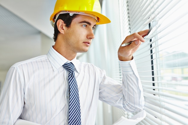 Ejecutivo con casco mirando a través de la ventana