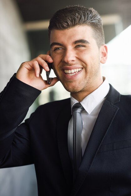 Ejecutivo elegante riéndose mientras habla por teléfono