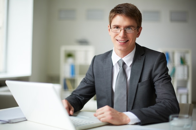 Foto gratuita ejecutivo con gafas escribiendo en el ordenador