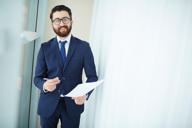 Ejecutivo con gafas sujetando contrato y bolígrafo