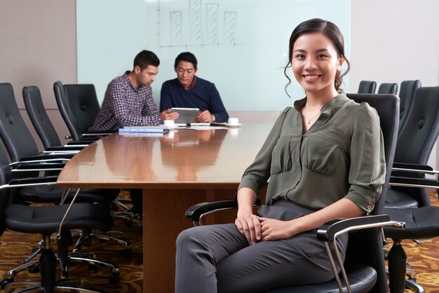 Ejecutivo de negocios femenino sentado en el escritorio de la oficina con sus colegas que trabajan en la plataforma digital en el fondo