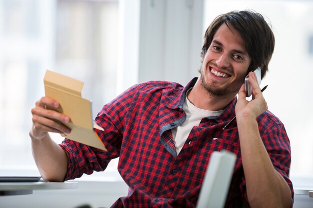 ejecutivo de negocios masculino que escribe en la libreta mientras se habla por teléfono móvil