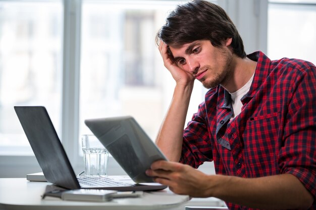 Ejecutivo de operaciones de sexo masculino que mira la tablilla digital