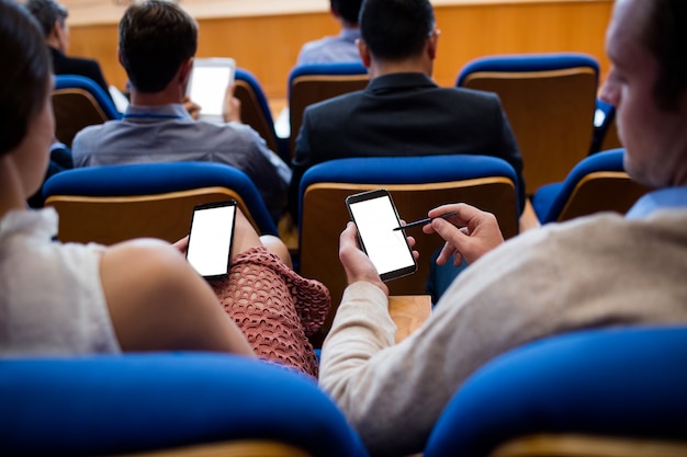 Ejecutivos de negocios que participan en una reunión de negocios usando un teléfono móvil