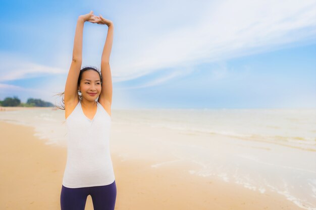 El ejercicio asiático hermoso de la mujer del deporte joven hermoso del retrato corre y que activa en la playa y el mar al aire libre de la naturaleza