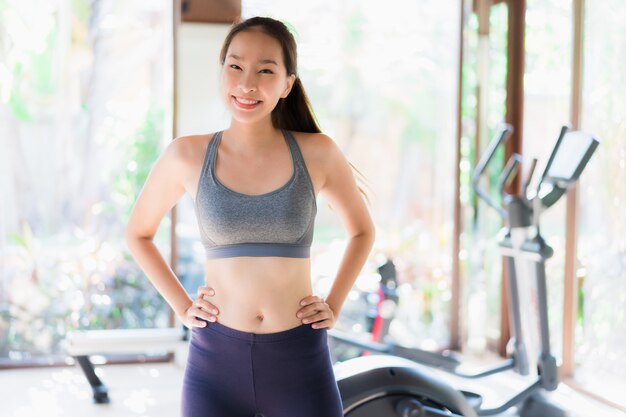 Ejercicio asiático joven hermoso de la mujer del retrato con el equipo de la aptitud en interior del gimnasio