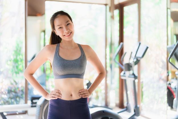 Ejercicio asiático joven hermoso de la mujer del retrato con el equipo de la aptitud en interior del gimnasio