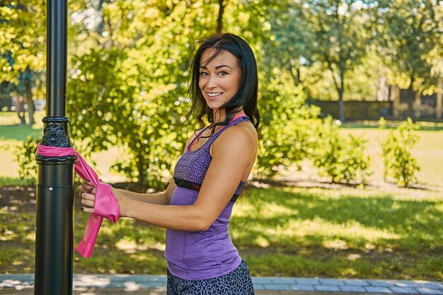 Ejercicio femenino deportivo positivo con tiras trx en un parque de otoño.