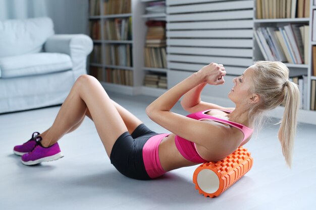 ejercicios de entrenamiento de mujer rubia con rodillo de espuma