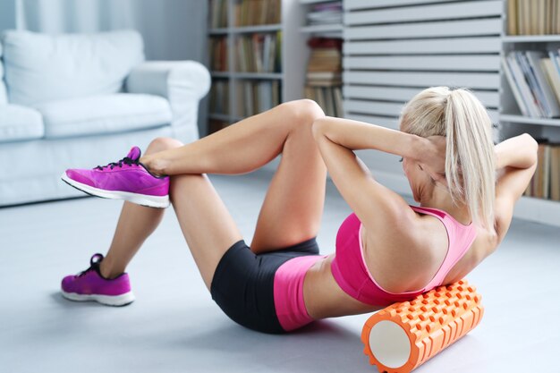 ejercicios de entrenamiento de mujer rubia con rodillo de espuma