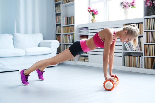 ejercicios de entrenamiento de mujer rubia con rodillo de espuma