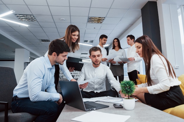 Elaboración de plan de negocios. Grupo de jóvenes autónomos en la oficina conversando y sonriendo