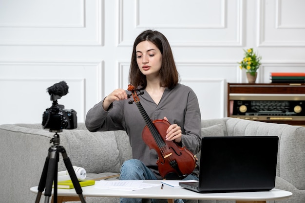 Elearning de forma remota en casa dando clases de violín joven linda hermosa niña explicando