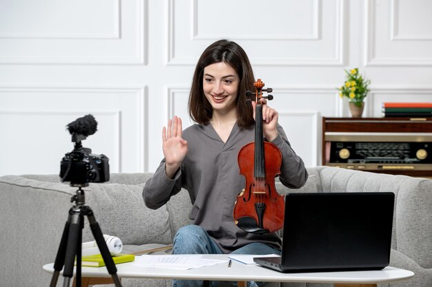 Elearning joven linda hermosa chica remotamente en casa dando clases de violín grabando video