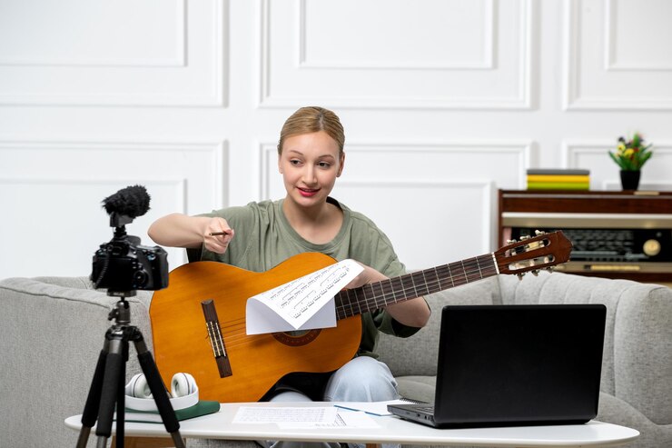 Foto gratuito elearning joven linda hermosa chica remotamente dando clases de guitarra en casa emocionada