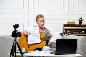 Foto gratis elearning joven linda hermosa chica remotamente dando clases de guitarra en casa con notas