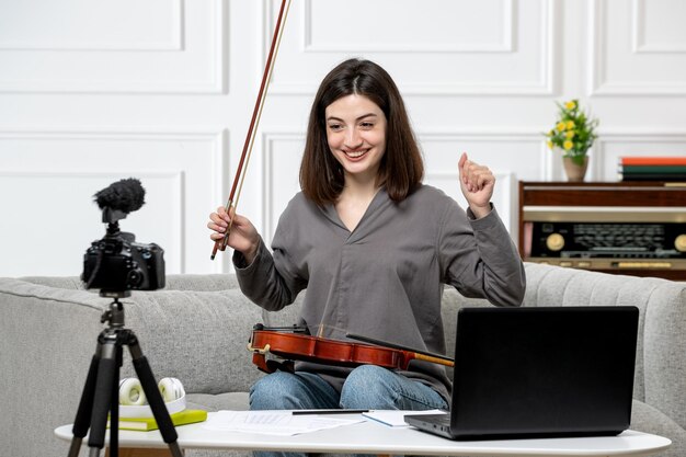 Elearning linda joven hermosa de forma remota en casa dando clases de violín muy feliz