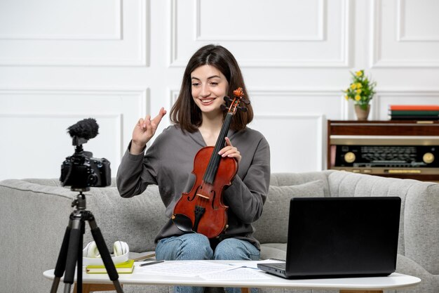 Elearning remotamente dando clases de violín en casa joven linda hermosa niña muy feliz