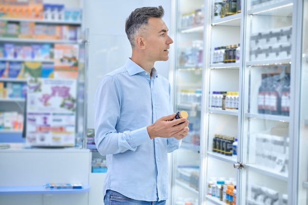 Elección de medicamentos. Un hombre eligiendo medicamentos en una farmacia.