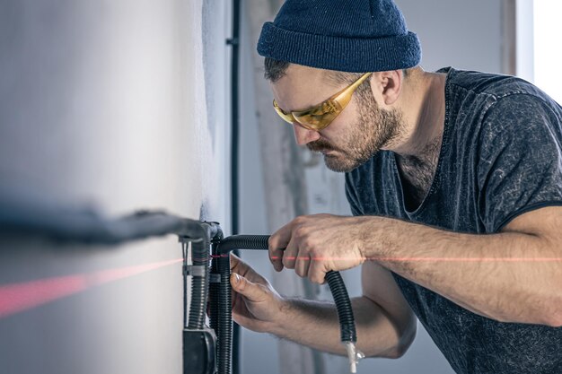 Un electricista está montando enchufes eléctricos en la pared blanca en el interior